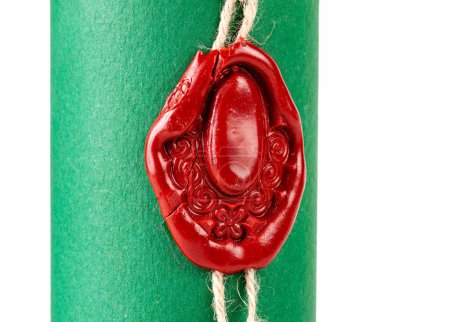 Altmodische mittelalterliche rote Wachssiegel mit einem kunstvollen Design bedruckt sichert eine Schnur um eine eng gerollte Schriftrolle mit lebendigem grünen Papier, Objekt Makro Detail extreme Nahaufnahme Siegelsymbolkonzept