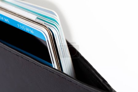 Makro-Detailaufnahme mehrerer Kreditkarten und Mehrwegkarten, die sauber in einer klassischen eleganten schwarzen Brieftasche gestapelt sind. Persönliches privates Geschäfts- und Finanzmanagement, Konzept der Zahlungsmethoden