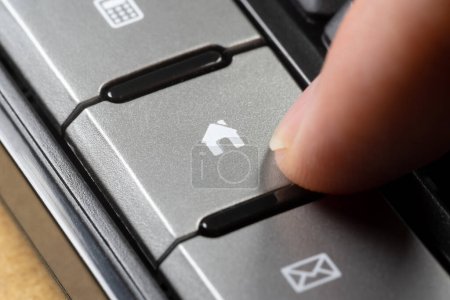 Close-up of a finger poised to press a keyboard button with a home icon, online internet real estate activities purchasing, buying selling browsing for financing, or renting properties, houses, home