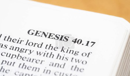 A close-up view capturing the text of Genesis 40;17 on a page within an open Bible, closeup, old testament books. Holy Bible christian catholic religious book simple concept. Creationism, Adam and Eve