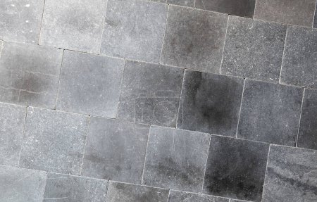 Dark gray square tiles neatly assembled textured background surface suitable for graphic design backgrounds or architectural textures, angle, simple backdrop, uneven coloring front view, frontal shot
