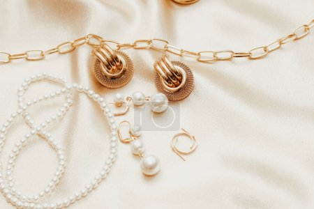 Téléchargez les photos : Bijoux femme, chaîne dorée, bijoux tendance sur fond de soie. - en image libre de droit