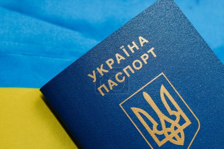 Ukrainischer Pass mit der Flagge der Ukraine auf einem Holztisch.