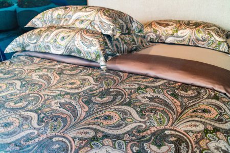 Téléchargez les photos : Linge de lit design paisley élégant sur un lit double confortable dans une vue rapprochée avec des oreillers assortis - en image libre de droit
