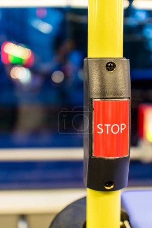 Photo for Extreme close up of red stop request button on yellow pole for public bus with obscured seat and window in background - Royalty Free Image