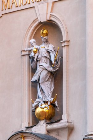 Photo for Gilded figure of the Madonna and child in a recessed alcove in an exterior wall with Mary holding baby Jesus on her arm standing on an orb with serpents - Royalty Free Image