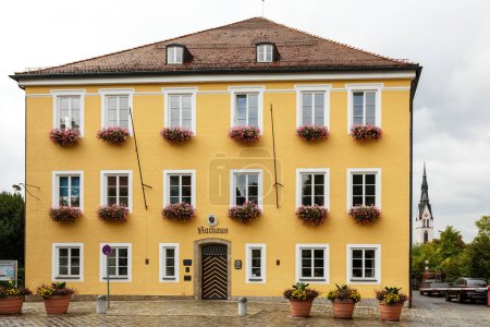 Téléchargez les photos : Façade du bâtiment jaune à étages dans le style architectural allemand, avec des plantes et des fleurs sur les appuis des fenêtres - en image libre de droit