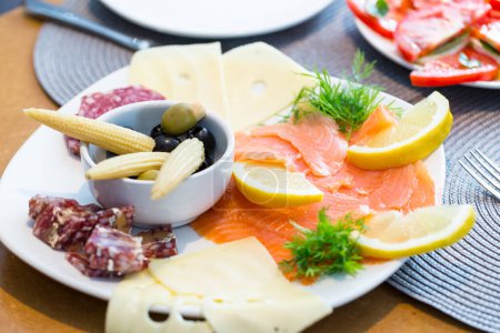 Foto de Placa de delicioso antipasto con salmón ahumado, queso, salami, aceitunas y maíz bebé - Imagen libre de derechos