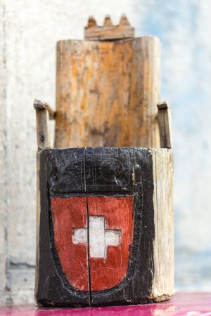 Téléchargez les photos : Petit trône en bois grossièrement sculpté avec un couteau avec croix blanche du drapeau suisse sur le devant, gros plan sur fond gris - en image libre de droit