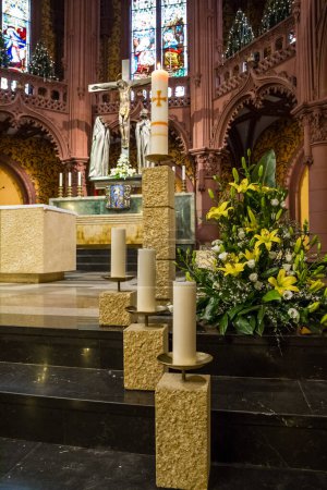 Foto de Velas votivas blancas decorativas en una iglesia de pie sobre columnas de oro texturizado que suben escaleras hasta el altar - Imagen libre de derechos