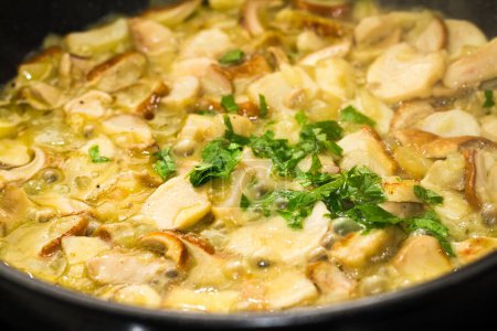 Téléchargez les photos : Cuisson de champignons tranchés dans une casserole avec sauce et persil. - en image libre de droit