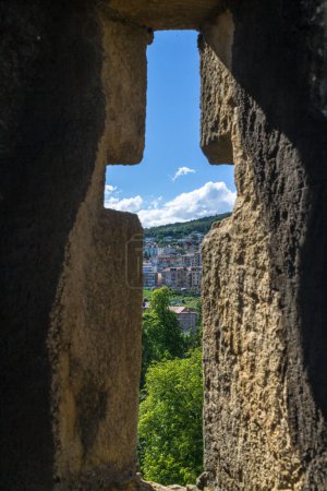 Téléchargez les photos : Ouverture en forme de croix dans un mur de château médiéval historique en pierre fortifié contre l'attaque avec la fente permettant aux archers et aux soldats de tirer leurs armes - en image libre de droit