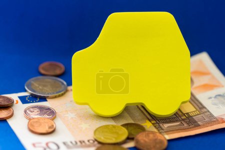 Téléchargez les photos : Fermer Concept Still Life of Yellow Car Cut Out on Blue Studio Background with Euro Paper Money and Coins - Image conceptuelle sur les coûts d'investissement de la propriété du véhicule - en image libre de droit