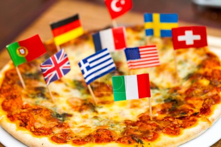 Téléchargez les photos : Différents drapeaux internationaux coincés dans la pizza cuite. - en image libre de droit