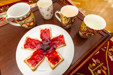 Téléchargez les photos : Toast et confiture de baies disposés dans un motif rayonnant et servis sur une assiette et sur un plateau en bois avec des tasses de boisson - en image libre de droit