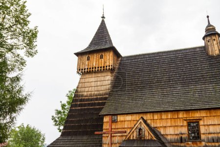 Téléchargez les photos : Chapelle rurale vieillissante construite en bois dans un style architectural classique près de grands arbres et un ciel gris - en image libre de droit