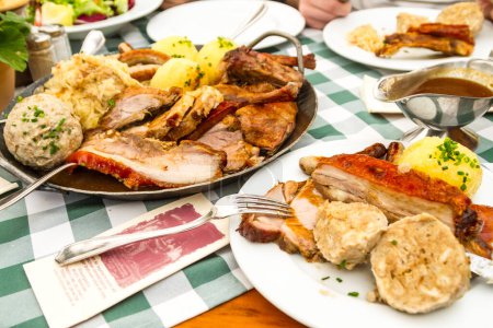 Téléchargez les photos : Repas abondant servi en plein air au restaurant avec divers plats de viande en plus de la sauce placée sur la nappe à carreaux verts et blancs - en image libre de droit
