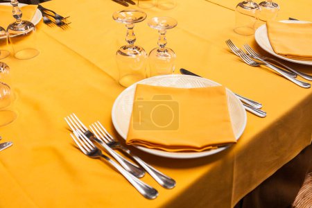 Téléchargez les photos : Gros plan d'une table dressée dans un restaurant italien. La serviette et la nappe sont de couleur pêche. - en image libre de droit