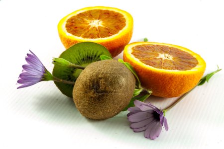 Téléchargez les photos : Fruits frais orange et kiwi aux fleurs lilas, fond blanc. - en image libre de droit
