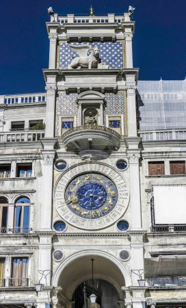 Téléchargez les photos : Tour de l'Horloge à Venise Italie avec le lion vénitien ailé sur la place Saint-Marks vue d'en bas contre un ciel bleu - en image libre de droit