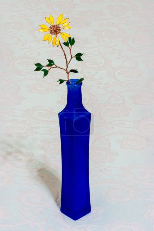 Foto de Flor amarilla en botella azul aislada en blanco. - Imagen libre de derechos