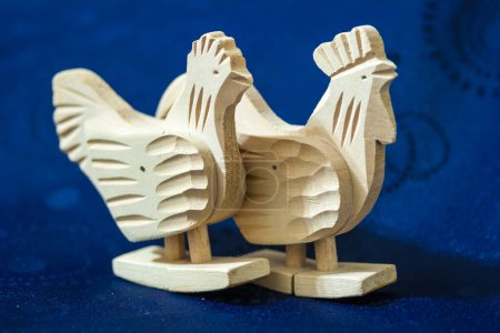 Téléchargez les photos : Vue de deux poulets en bois sculptés à la main sur fond bleu. - en image libre de droit