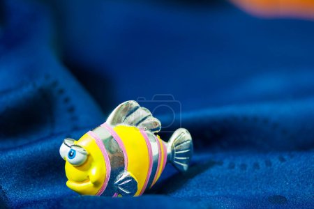 Téléchargez les photos : Jouet de bain poisson en plastique sur serviette de bain bleue. - en image libre de droit