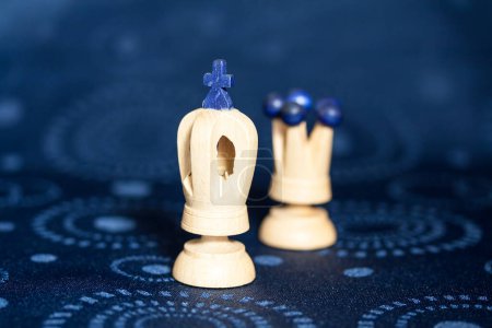 Photo for King and Queen carved white wooden chess pieces positioned side by side on a blue patterned background. - Royalty Free Image