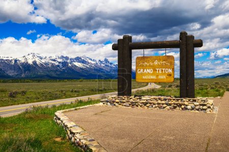 Señal de bienvenida en la entrada del Parque Nacional Grand Teton en Wyoming, con la cordillera Teton en el fondo.