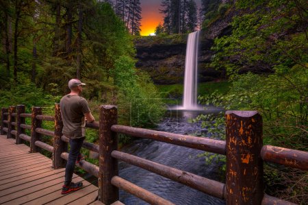Photo for Tourist looking at the South Falls in Silver Falls State Park, Oregon. Photographed at sunset. Long exposure. - Royalty Free Image