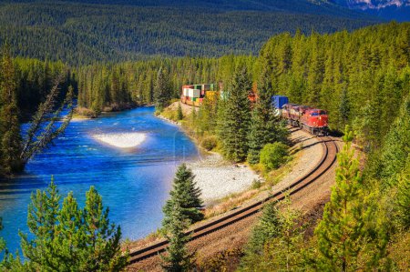 Photo for Train passing through the Morants Curve in Bow Valley with Bow River and the Rocky Mountains in the background, Banff National Park, Alberta Canada. - Royalty Free Image