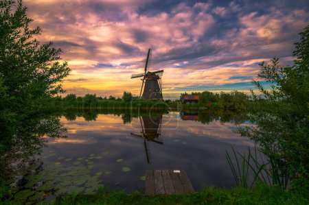 Téléchargez les photos : Coucher de soleil coloré au-dessus d'un vieux moulin hollandais et d'une rivière qui coule à Kinderdijk, Pays-Bas. - en image libre de droit