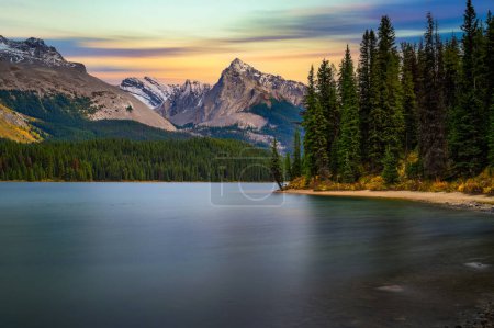 Sunset over Maligne Lake in Jasper National Park, Canada, with snow-covered peaks of canadian Rocky Mountains in the background. Long exposure.