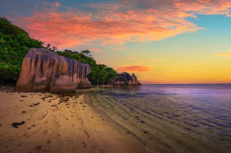Téléchargez les photos : Coucher de soleil coloré sur Anse Source Plage de Dargent sur l'île de La Digue, Seychelles, avec eau calme de l'océan Indien et d'étonnantes formations rocheuses de granit. - en image libre de droit