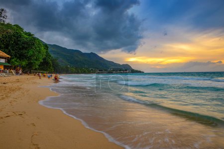 Téléchargez les photos : Beau Vallon, Seychelles - 12 février 2022 : Personnes marchant et faisant du sport sur la plage de Beau Vallon au coucher du soleil. Beau Vallon Beach est une plage très fréquentée sur l'île de Mahe. - en image libre de droit