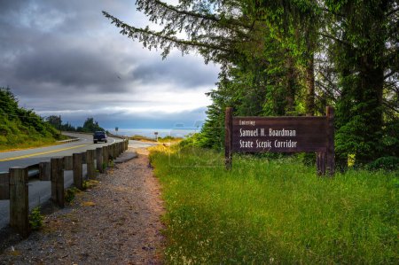 Foto de Camino que conduce a Samuel H. Boardman State Scenic Corridor en Oregon con señal de bienvenida y vegetación. - Imagen libre de derechos