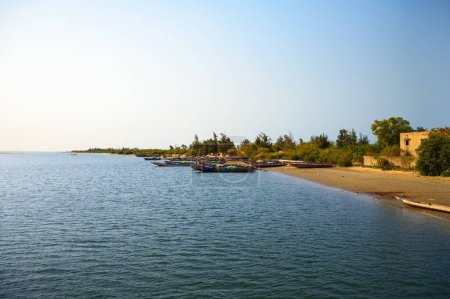 Foto de Joal Fadiouth, Senegal - 27 de febrero de 2023: Paisaje costero desde Ponte Joal Fadiouth en Senegal, mostrando barcos y una playa de arena. - Imagen libre de derechos