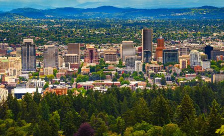 Luftaufnahme von Portland, Oregon, mit einer Stadtsilhouette vor bewaldeten Hügeln. Fotografiert vom Standpunkt der Pittock Mansion.