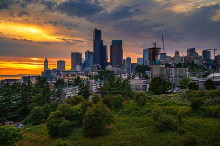 Dramatic sunset over Seattle skyline with visible greenery in the foreground, viewed from Dr. Jose Rizal Bridge.
