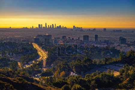 Hollywood Downtown bei Sonnenaufgang mit der Skyline von Los Angeles im Hintergrund und dem Verkehr auf dem US-101 Highway im Vordergrund.