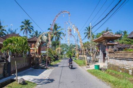 Foto de BALI, INDONESIA - 16 DE ABRIL DE 2017: Calles de Bali. Los polacos Penjor pueden ser vistos como parte de la celebración anual de Galungan. La gente puede ser vista. - Imagen libre de derechos