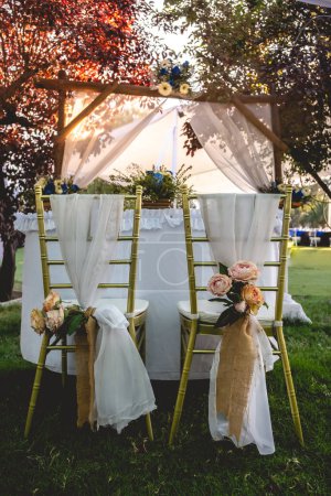 Téléchargez les photos : Bouquet de tournesol et de petites fleurs blanches dans une table de mariage avec des lunettes et un décor de table élégant au coucher du soleil - en image libre de droit