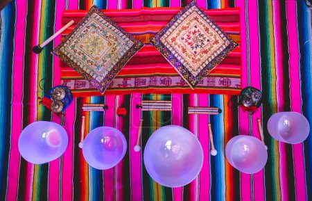 Photo for Big quartz singing bowls, chime bells and tingsha cymbals over a andean (peruvian) handwoven with purple light - Royalty Free Image