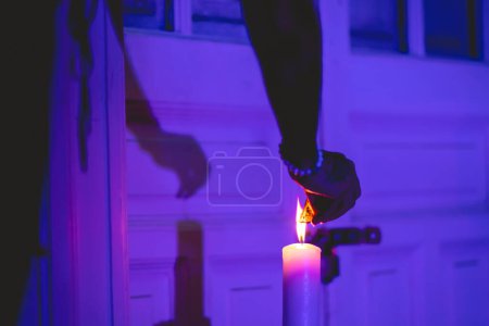 Photo for Hand burning a 'palo santo' (holy wood) in a flame of a candle with purple light - Royalty Free Image