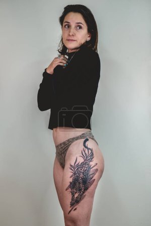 Téléchargez les photos : Belle femme avec un gros tatouage terminé d'un tigre dans la cuisse et les hanches après la séance de tatouage - en image libre de droit