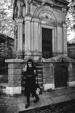 Téléchargez les photos : Stylish dark gothic girl in large ancient abandoned mausoleum with neoclassical style in a sunny day (in black and white) - en image libre de droit
