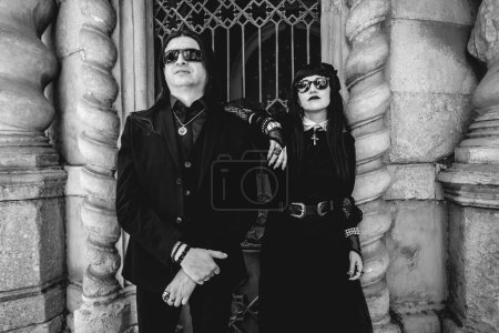 Téléchargez les photos : Stylish dark gothic couple in large ancient abandoned mausoleum with neoclassical style in a sunny day (in black and white) - en image libre de droit