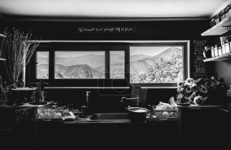 Téléchargez les photos : Intérieur d'une grande cuisine avec vue sur les montagnes en face de l'évier avec verres, vaisselle et casserole avec riz (en noir et blanc) - en image libre de droit