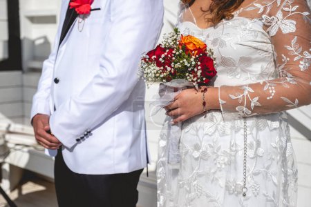 Téléchargez les photos : Le moment d'amour parfait : détail des mains du marié et de la mariée tenant le bouquet lors de la cérémonie de mariage - en image libre de droit