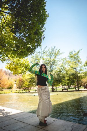 Photo for Enchanting latina charm: beautiful brunette model with a green knitted sweater in a sunny day in the park - Royalty Free Image